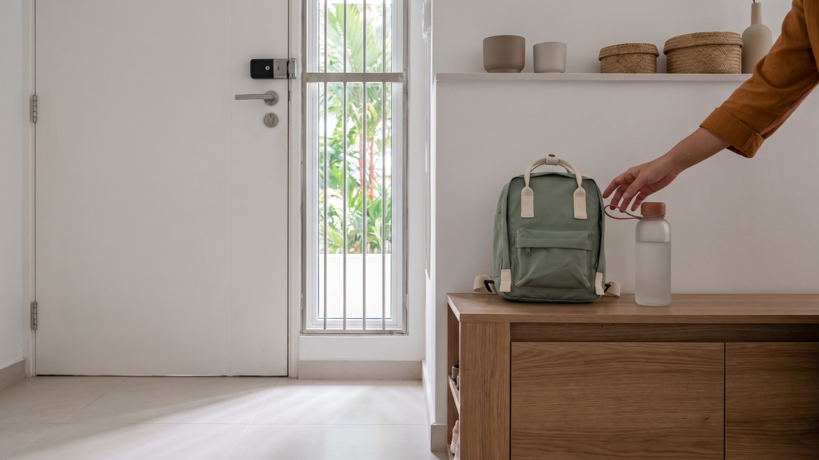 A small backpack and water bottle waiting by the front door of an HDB flat, packed for a morning at an early intervention centre.